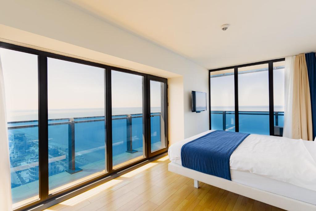 a bedroom with a bed and large windows at Guest Favorite Sea View Apartments Batumi in Batumi