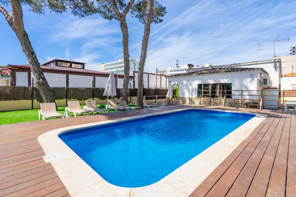 a pool on a deck with chairs and a house at Villa Els Pins in El Arenal