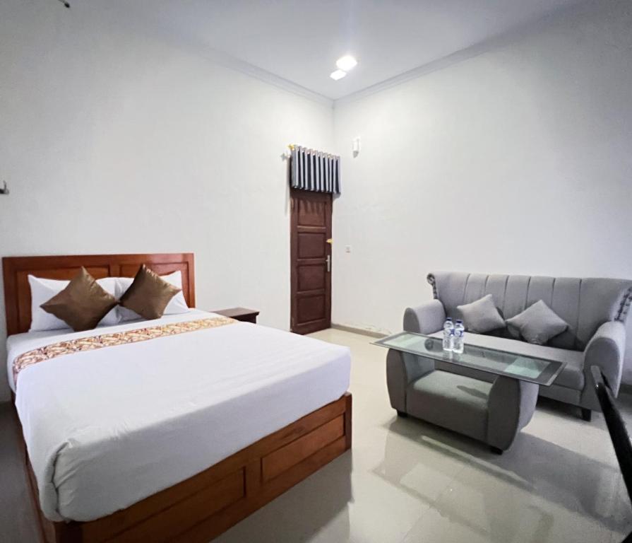 a bedroom with a bed and a couch at Guest House Primitif in Temon