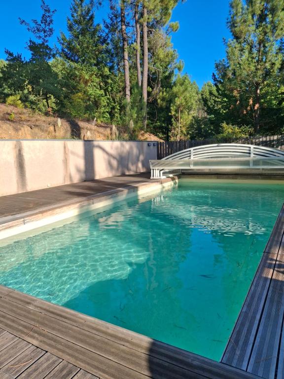 a swimming pool with a wooden deck and blue water at Maison zen in Laval-Pradel