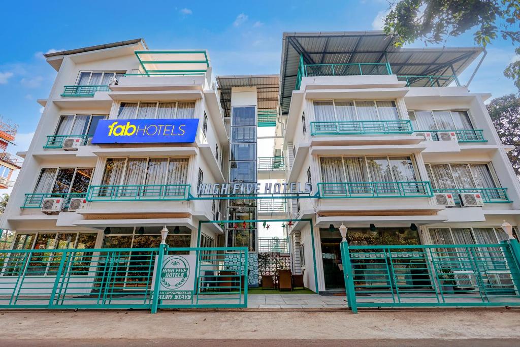 a white building with a blue sign on it at FabHotel High Five - Nr Vagator Beach in Assagao