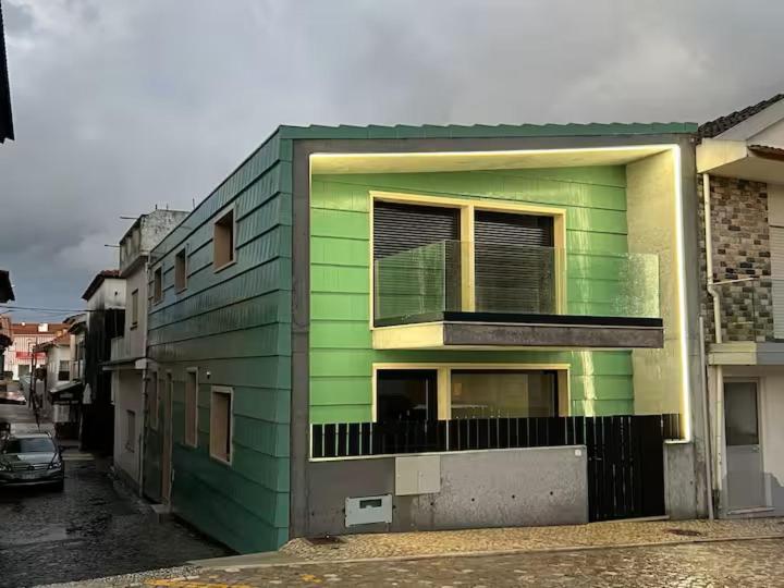 a green building with a balcony on a street at casa da Inês in Vieira de Leiria