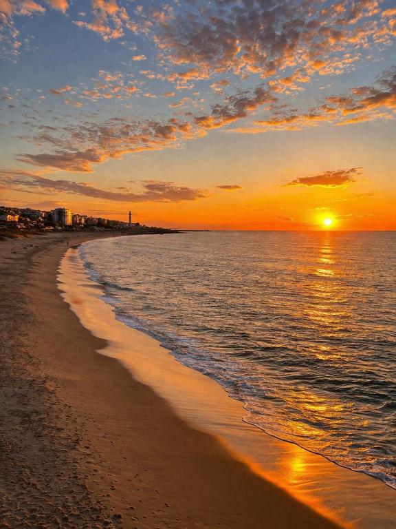 a beach with the sun setting over the water at Oporto Beach Apartment in Vila Nova de Gaia