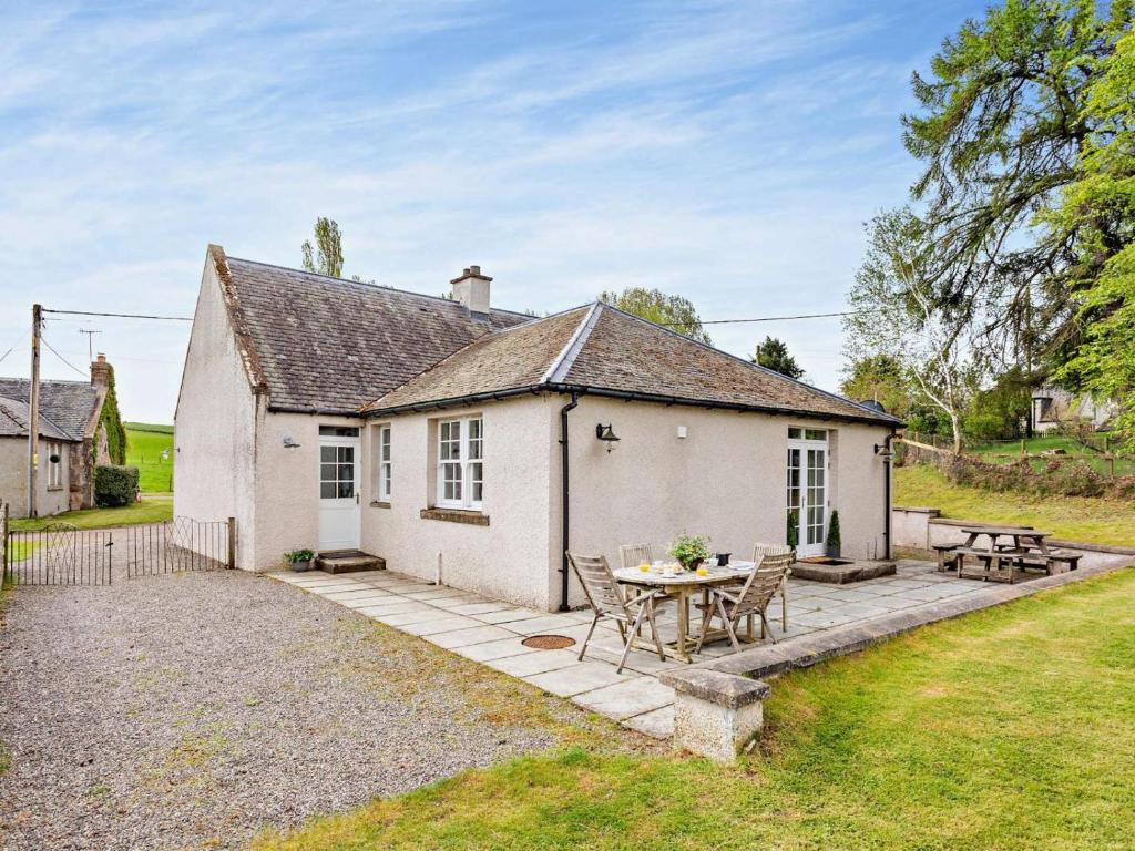 a white cottage with a table and chairs at 3 Bed in Dingwall oc-ca388 in Cononbridge