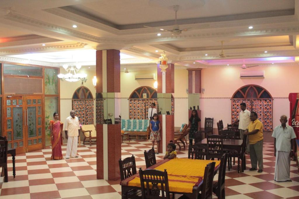 a group of people in a room with tables and chairs at Chettinaadu Narayana Inn in Kānādukāttān