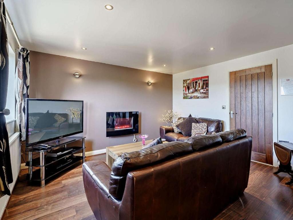a living room with a leather couch and a flat screen tv at 2 Bed in Blackburn oc-finch in Blackburn