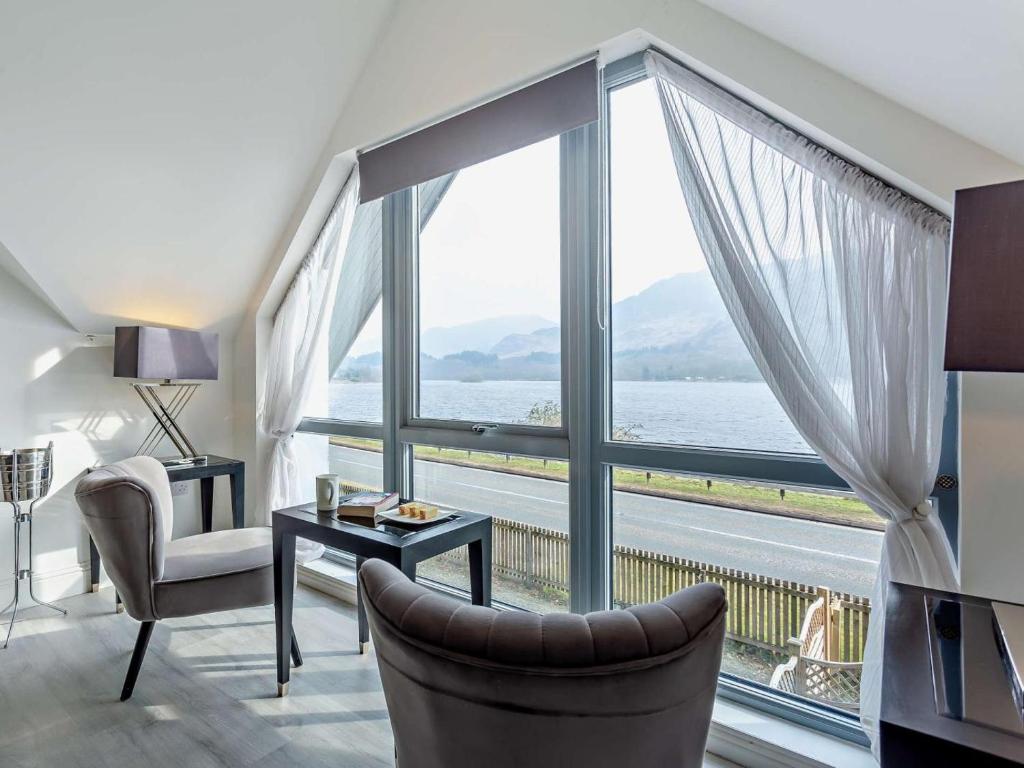 a living room with a large window with a view of the water at 1 Bed in Crieff oc-58797 in Saint Fillans