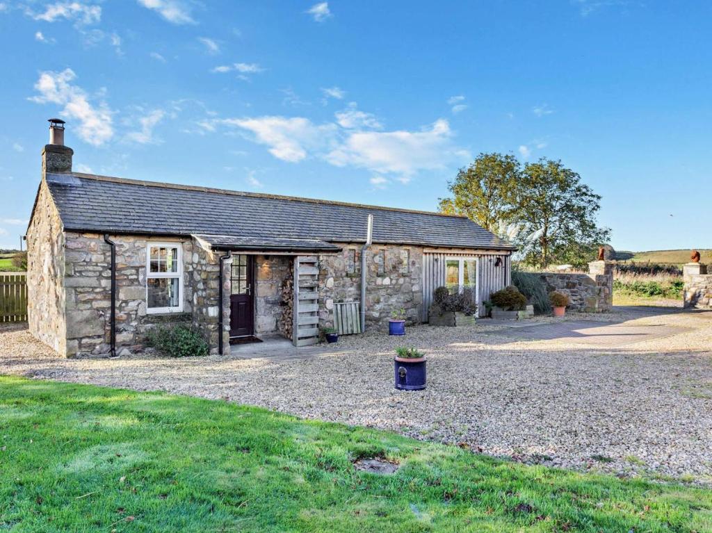 an old stone cottage with a gravel driveway at 1 Bed in Forres oc-32129 in Burghead