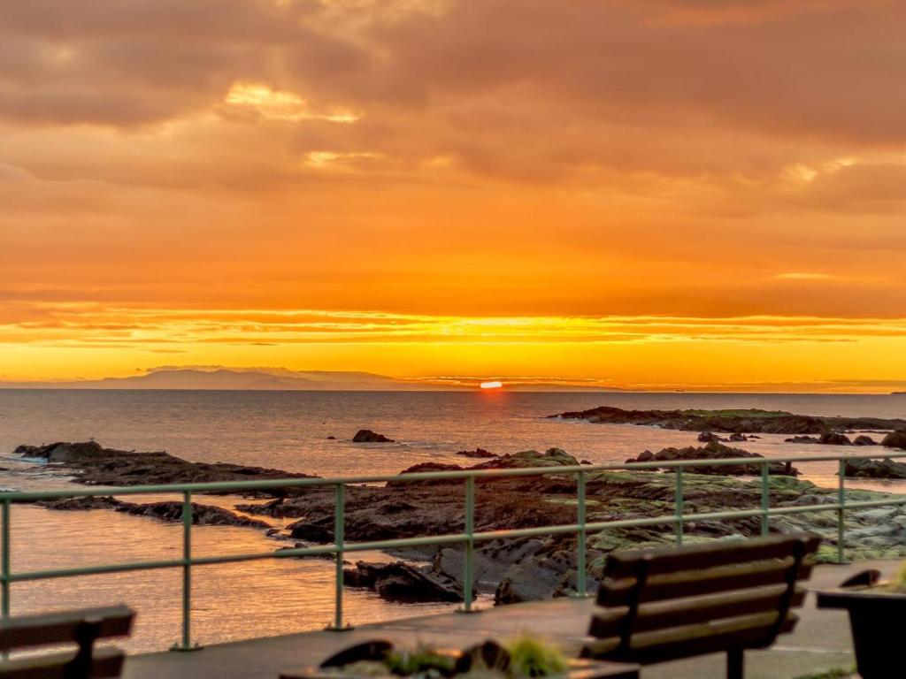a sunset over a beach with a bench and the ocean at 2 Bed in Anstruther oc-80648 in Pittenweem