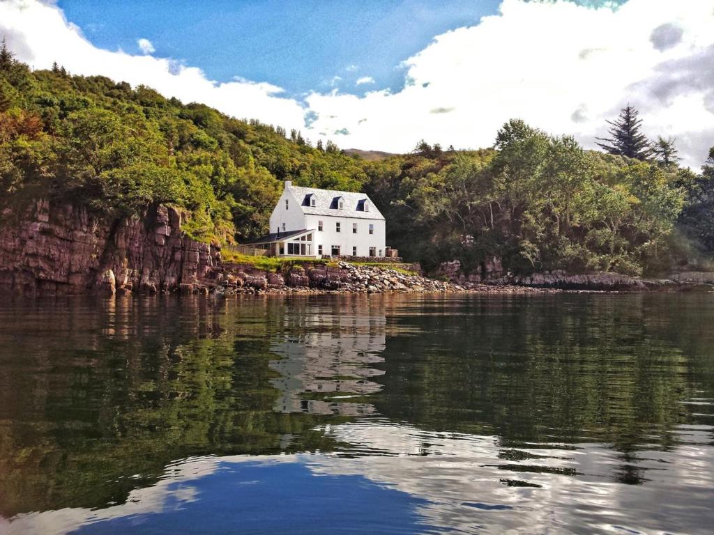 a white house sitting on the edge of a body of water at 6 Bed in Ullapool oc-ca259 in Ullapool