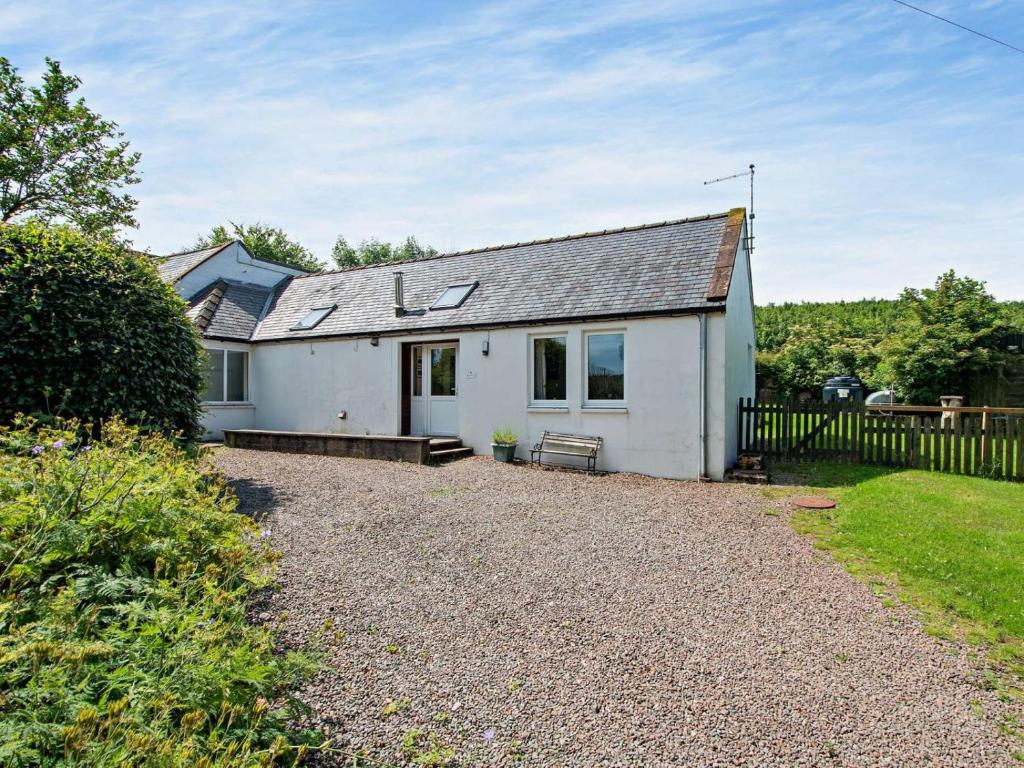 a white house with a fence and a gravel driveway at 1 Bed in Castle Douglas oc-ca371 in Castle Douglas