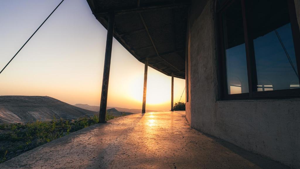 a building with the sun setting in the horizon at Zman Midbar Eco Spirit Lodge for Peace in Arad