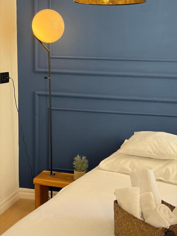 a bed with a yellow lamp next to a blue wall at Bright Romantic Studio near sea in Kaštela