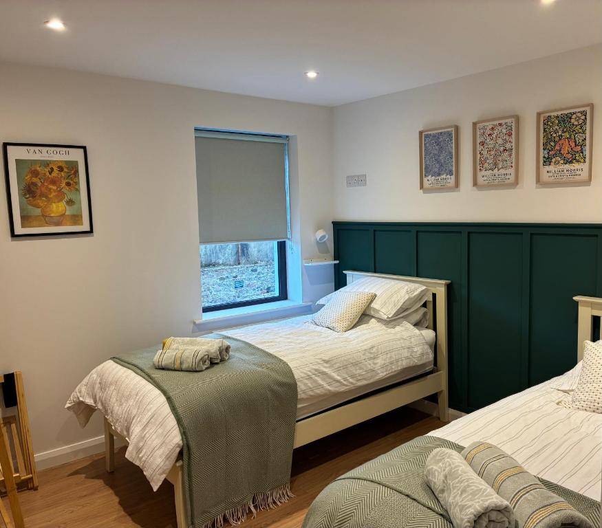 a bedroom with two beds and a window at Clare Escape Ballycastle - Luxury town centre apartment, walk to beach & harbour, near Giants Causeway in Ballycastle