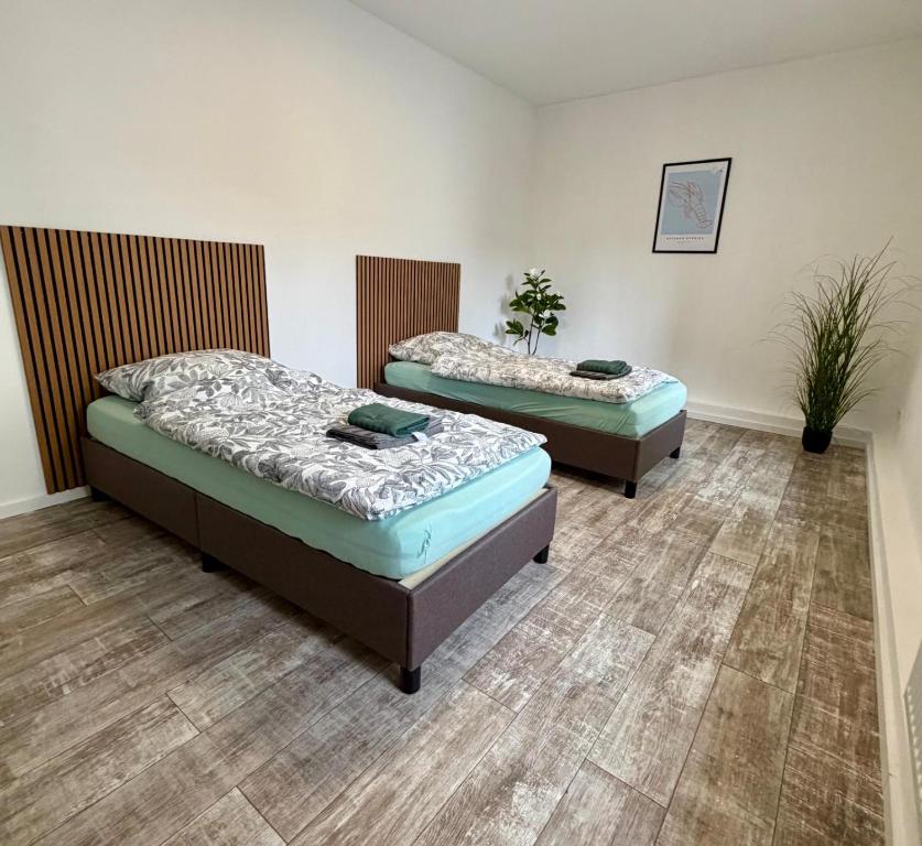 two twin beds in a room with wood floors at Modernes Apartment im Grünen in Kroppach