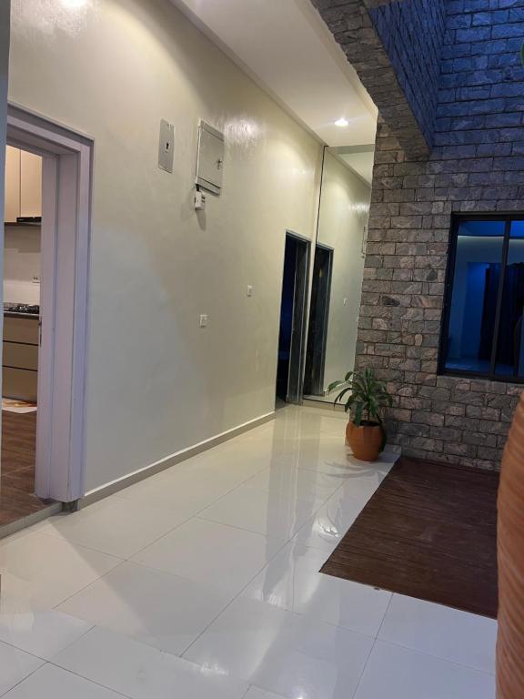 a large room with a white floor and a brick wall at The Mishkan Apartments in Kaduna