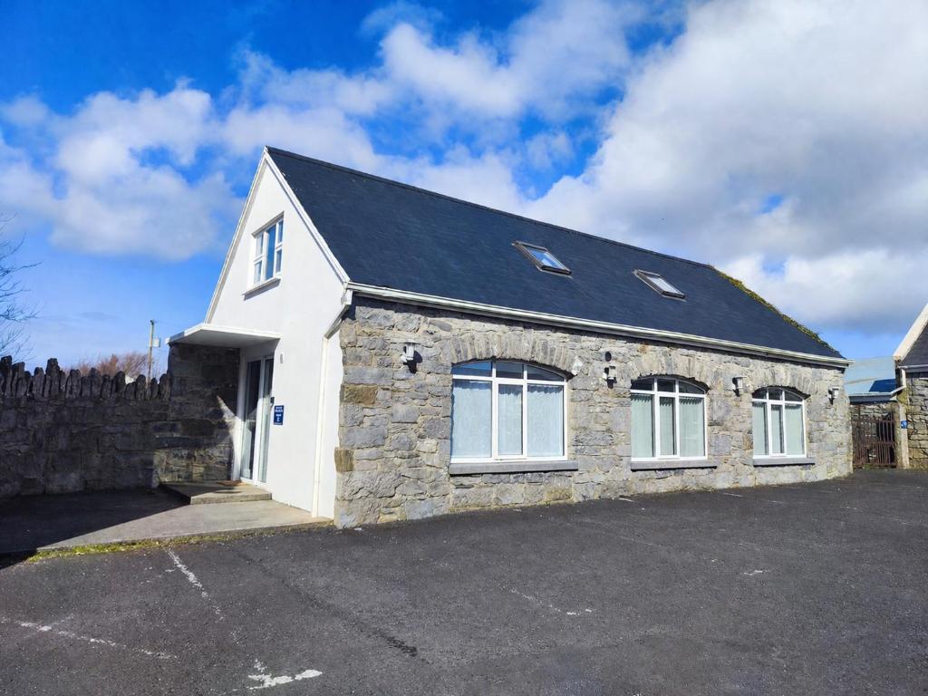 a stone house with a black roof at Aran View Holiday Homes Doolin - The Courtyard House - Sleeps 9 in Knockfin Cross Roads