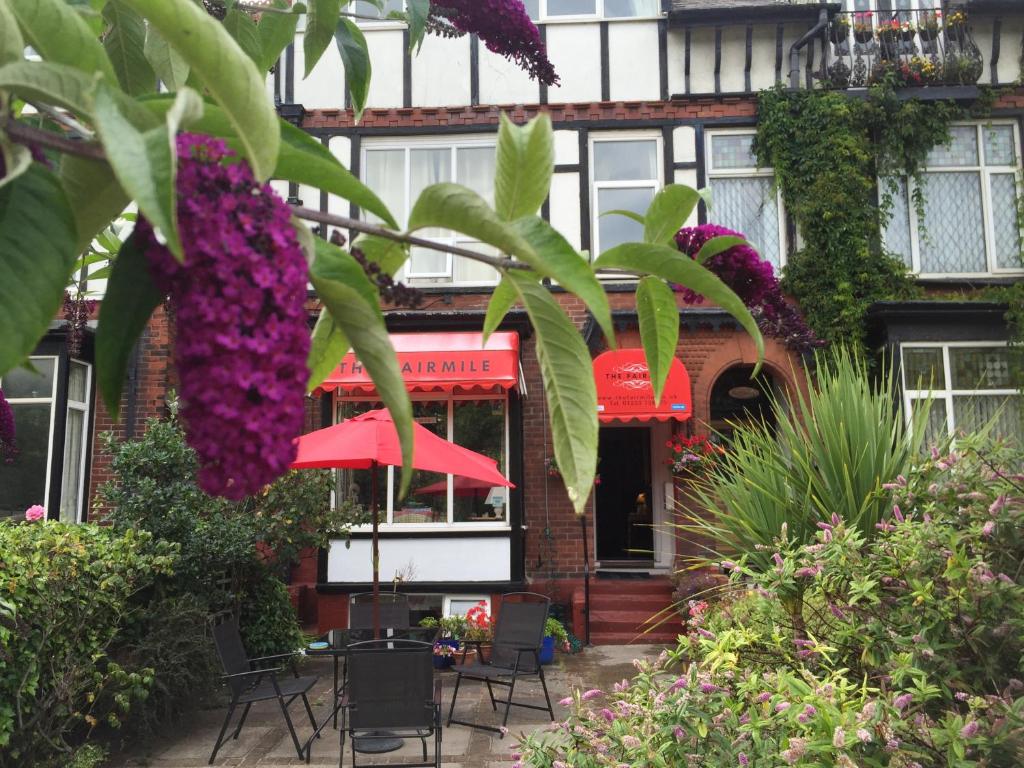 um edifício com flores roxas, mesas e cadeiras em The Fairmile em Lytham St Annes