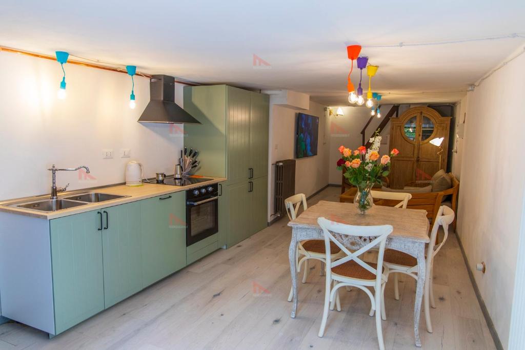 a kitchen with green cabinets and a table with chairs at Casa Torre Adults Only storia e relax a Fiorenzuola in Fiorenzuola di Focara