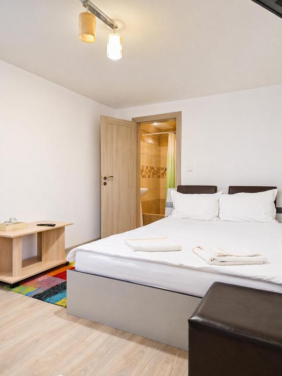 a bedroom with a large white bed and a table at NATURA Garden in Cluj-Napoca
