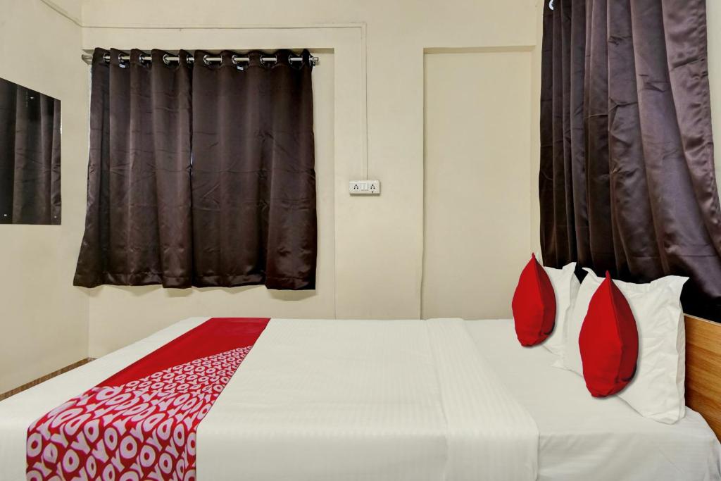 a bedroom with a large bed with red pillows at Hotel O Sai Avenue in Pune
