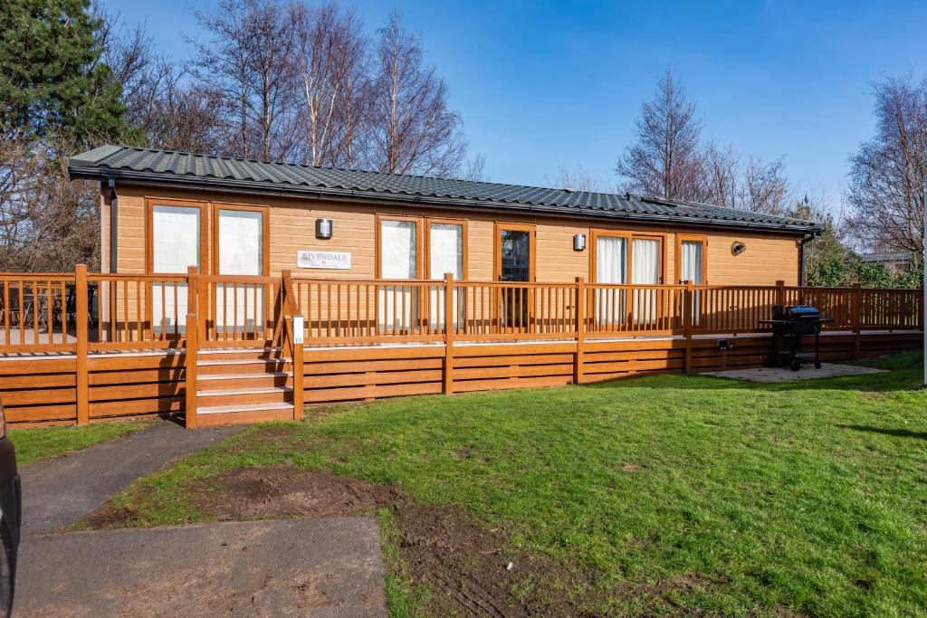 a wooden cabin with a fence and a yard at Rivendale Lodge in Port Seton