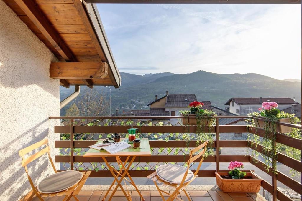 a table and chairs on a balcony with a view at Grace house holiday in San Fedele Intelvi