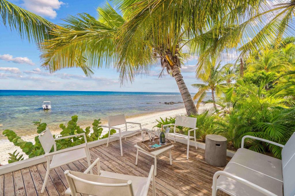 a beach with chairs and palm trees and the ocean at Villa Marea - Exceptional Beachfront Sanctuary in Tamarin
