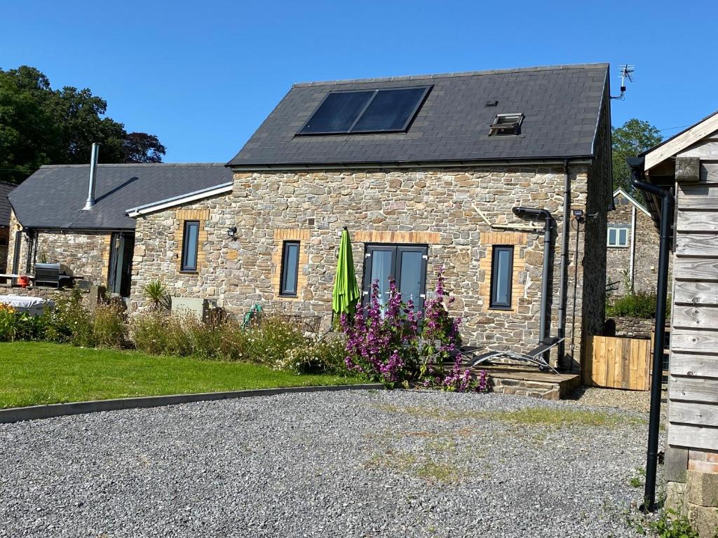 a stone house with a solar roof and a driveway at The Threshing Barn Loft in Pont-y-Berem