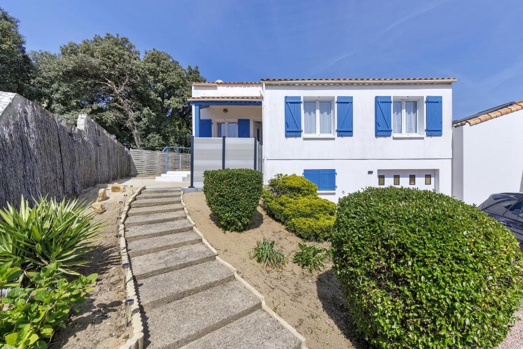 a white house with blue windows and bushes at Le Cœur de Tranche - proche mer in La Tranche-sur-Mer