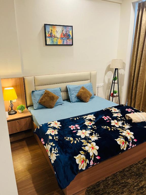 a bedroom with a bed with a blue blanket with flowers at Kervan stays in Greater Noida