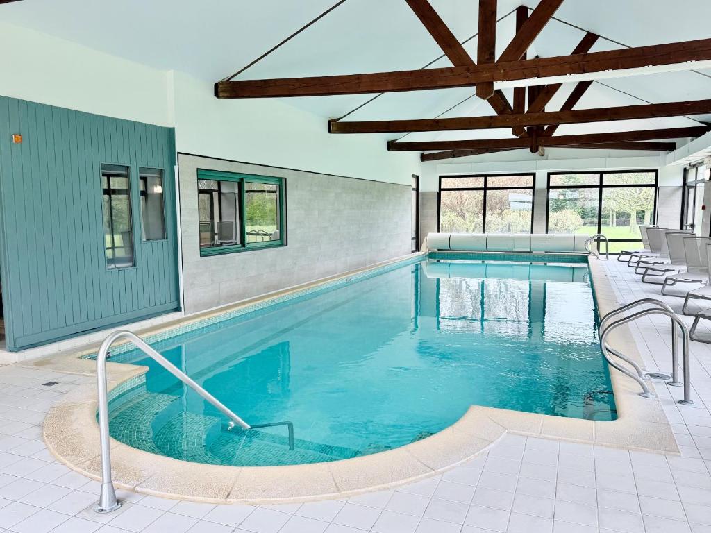 a large swimming pool with blue water in a building at Holiday Inn Calais Coquelles by IHG in Coquelles