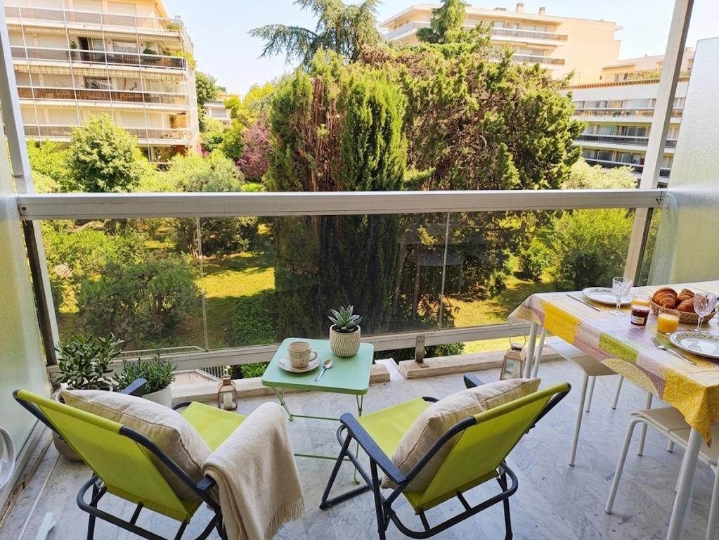 a balcony with a table and chairs and a large window at logement climatisé à Juan les Pins dans résidence avec piscine in Juan-les-Pins