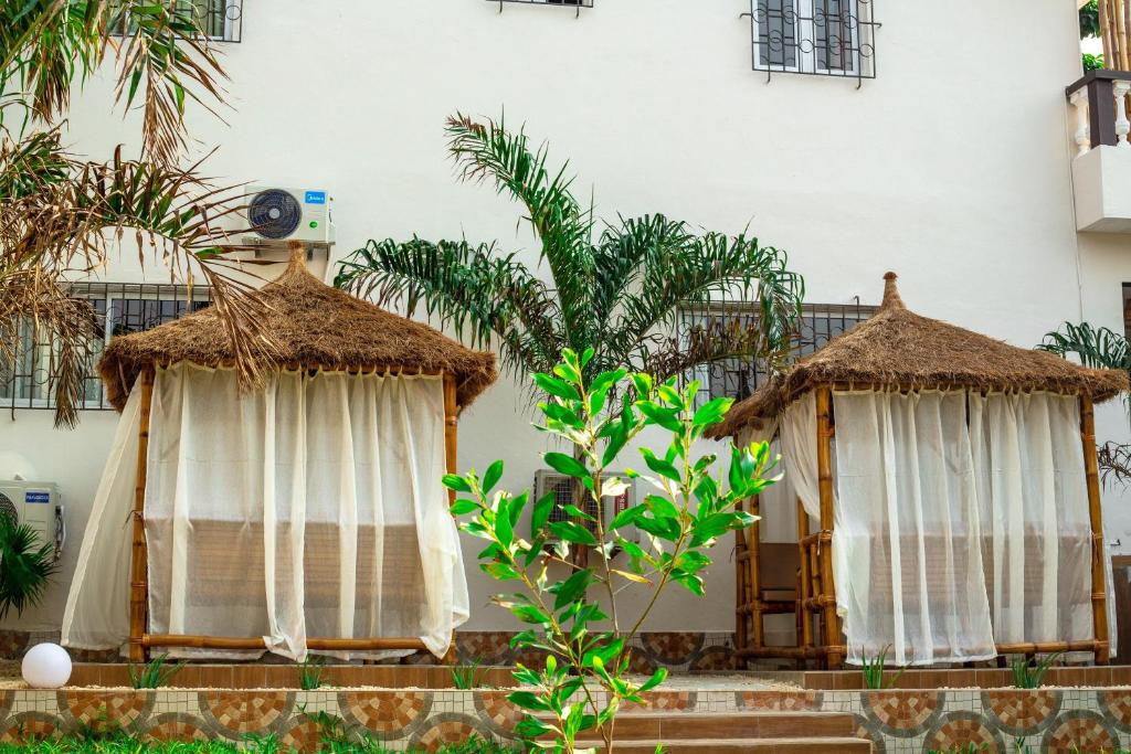 two thatch huts with curtains in front of a building at Chambre La Villa Kalanga in Abidjan