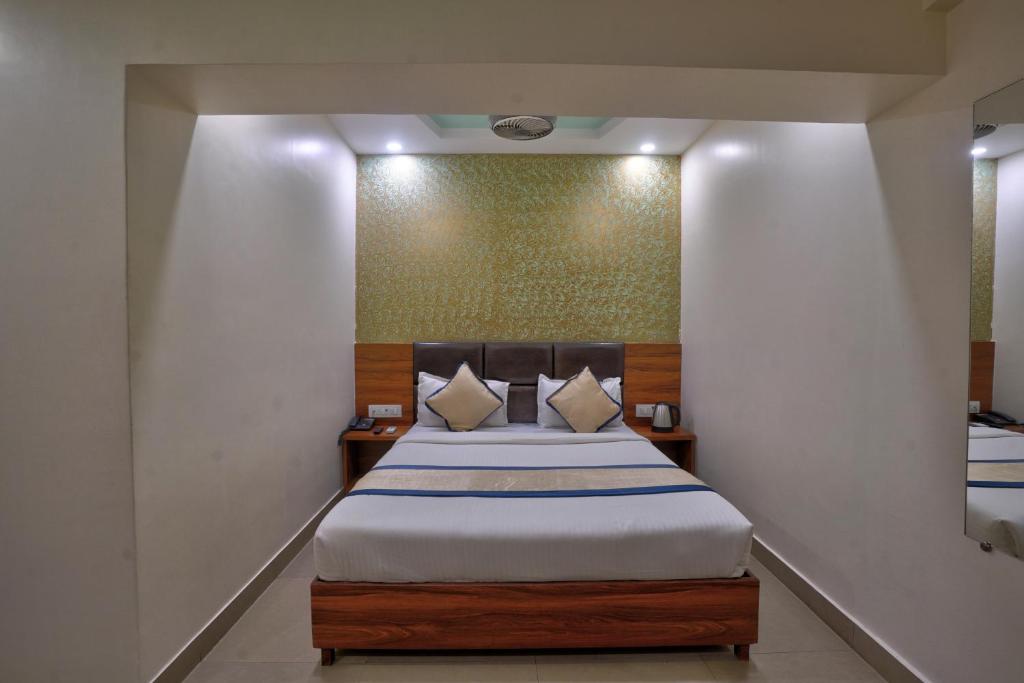 a bedroom with a large bed with white sheets at Hotel Saineel Residency in Mumbai