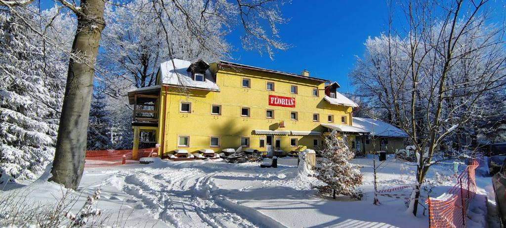 a yellow building with a sign on it in the snow at Chata Florian in Adolfov
