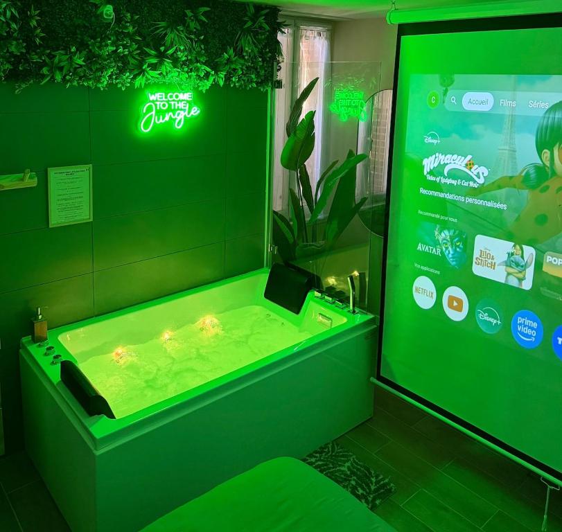 a green bathroom with a tub with a video screen at La Jungle - A71 - Jacuzzi et Cinéma in La Chapelle-Saint-Ursin