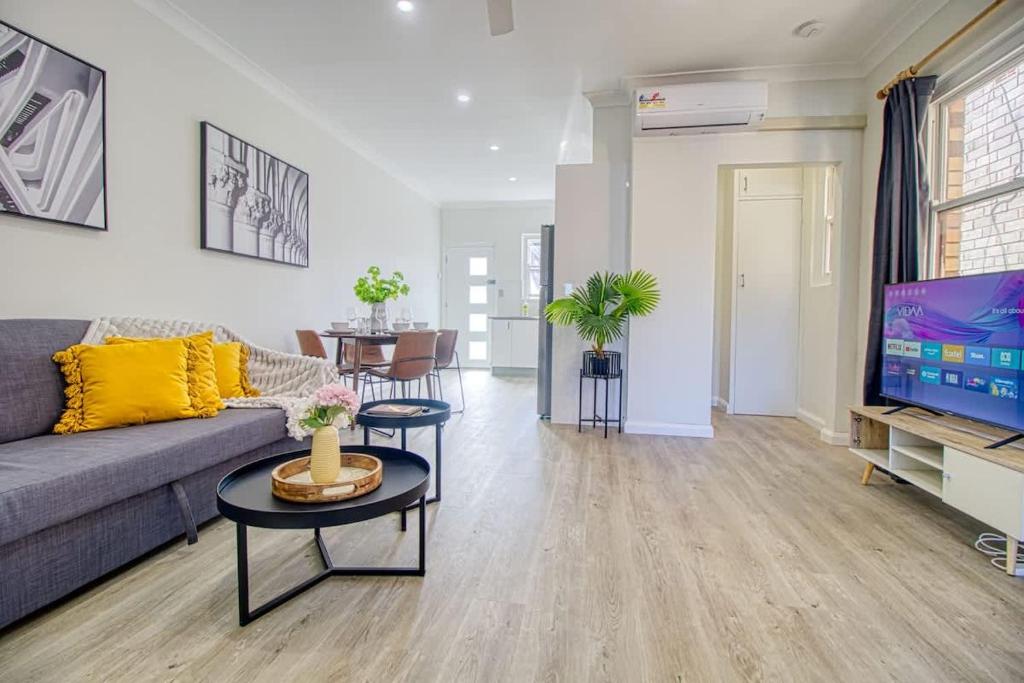 a living room with a couch and a tv at Coastal & Connected Summer Resort Parking in Cronulla