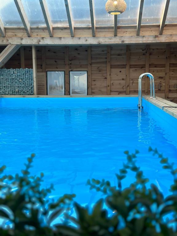 a swimming pool in a wooden house with a blue pool at Domki Złote Piaski Kryty Basen Sauna Jacuzzi in Jastrzębia Góra