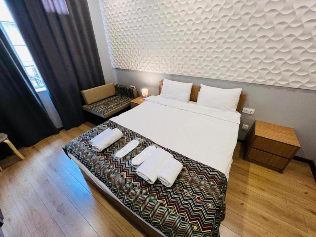 a bedroom with a large bed with two white towels at Downtown Hotel in Tbilisi City