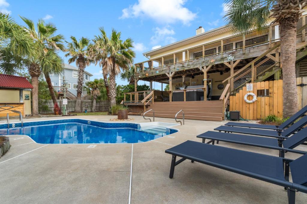 a house with a swimming pool and palm trees at Flip Side Oasis Beach House in Pensacola Beach