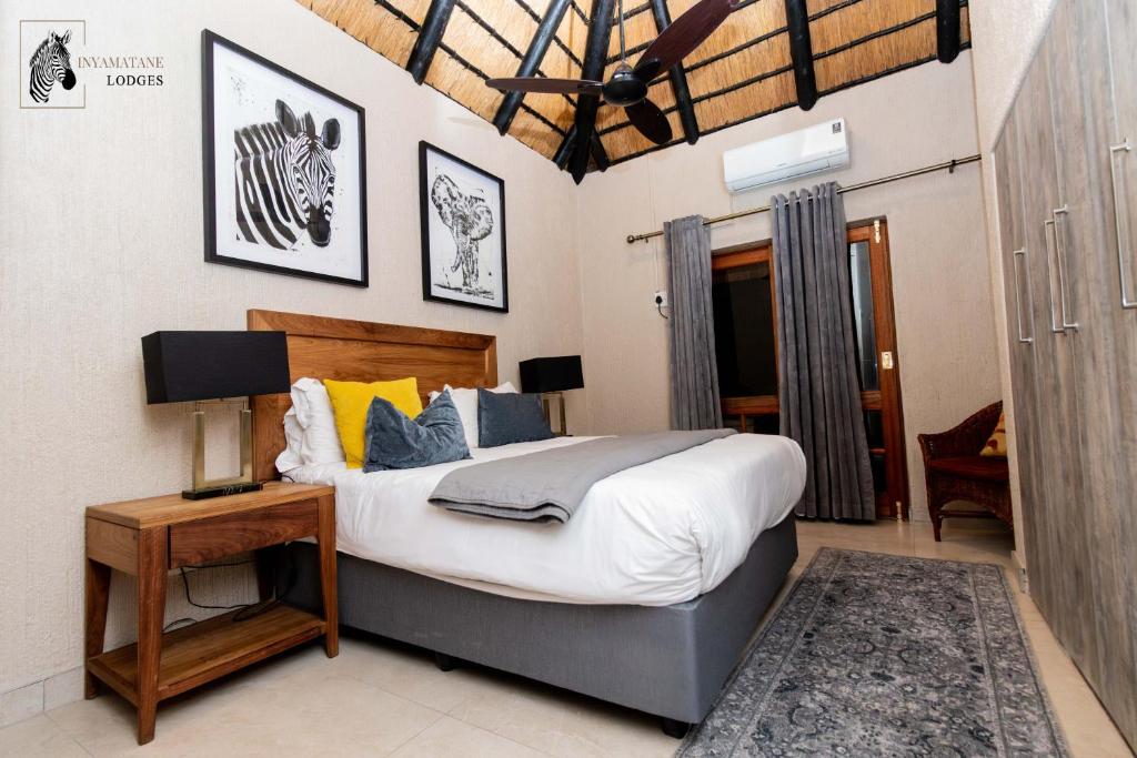 a bedroom with a king sized bed and a table at INYAMATANE LUXURY LODGES at Kruger Park Lodge in Hazyview