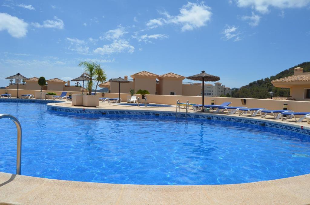 una gran piscina con sillas y sombrillas en Buena Vista 7708 - Resort Choice, en La Manga del Mar Menor