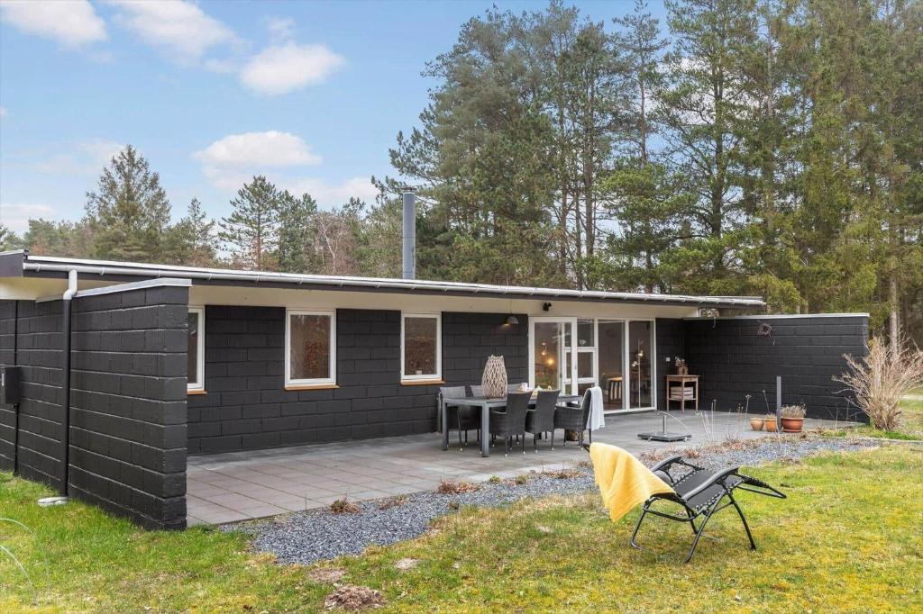 a black house with a patio and a table at 84307-8400-Skovduevej-4 in Fuglslev
