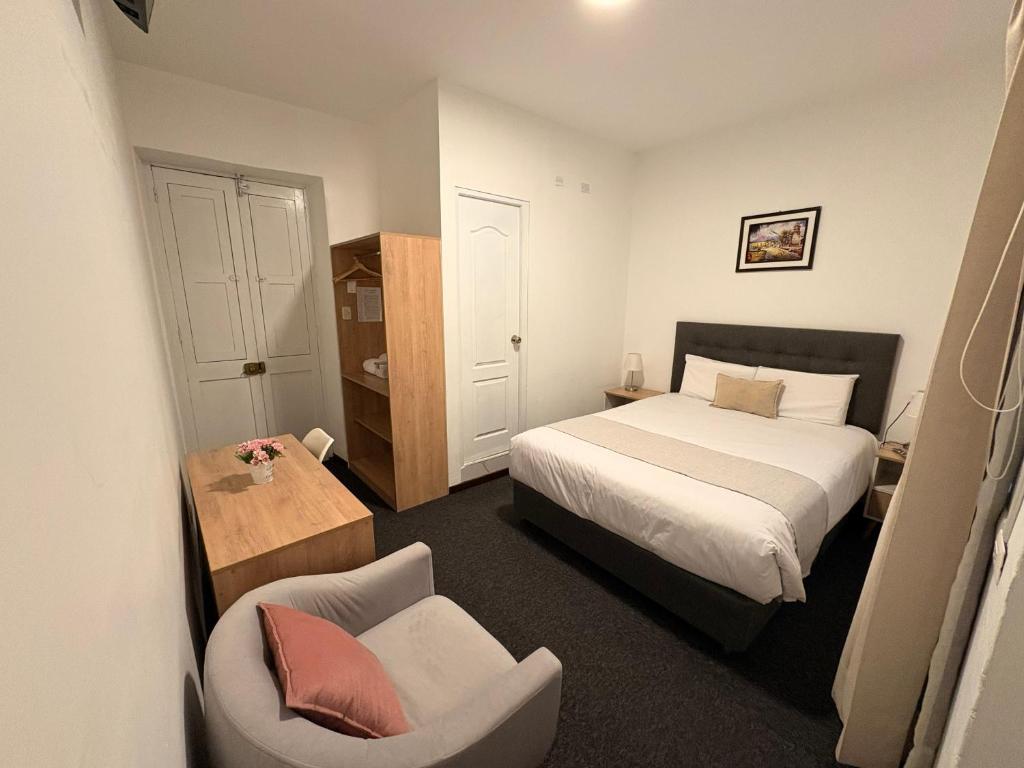 a small bedroom with a bed and a chair at Hotel Altara AQP in Arequipa