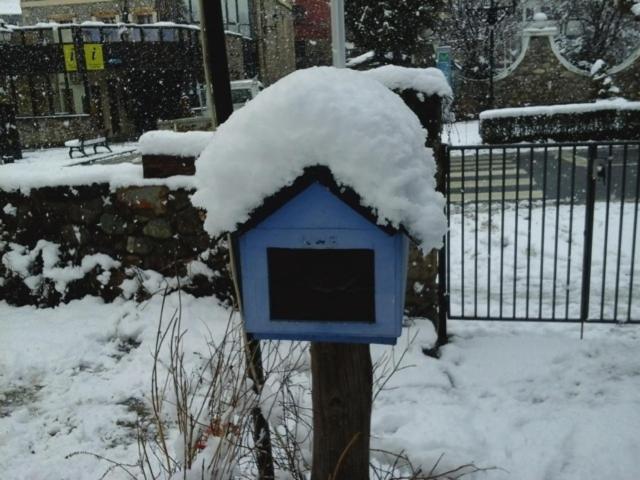 uma caixa de correio azul coberta de neve ao lado de uma cerca em Albergue Pájaro Loco em Castejón de Sos