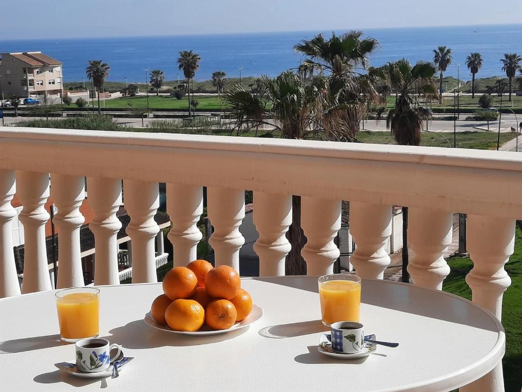 a plate of oranges on a table with two cups of orange juice at Sea View Apartman Daimus in Daimuz