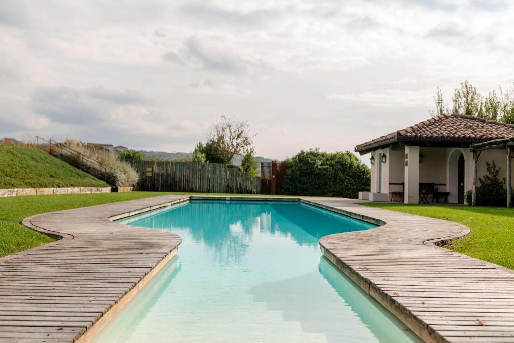 a swimming pool with a wooden path and a house at Relais dei Poderi Einaudi in Dogliani