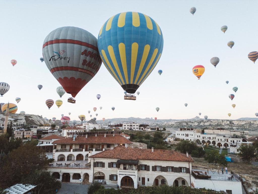 a group of hot air balloons flying over a city at Garden Inn Cappadocia in Göreme