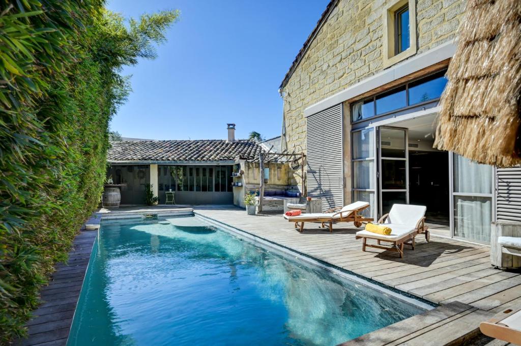 a swimming pool with a deck and a house at La Pause Camarguaise in Saint-Laurent-dʼAigouze